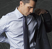 Black-and-white portrait of a male model with slicked side-parted hair, putting on a suit jacket