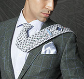 Black-and-white portrait of a male model with short side-swept hair, wearing a tweed check blazer and pocket square